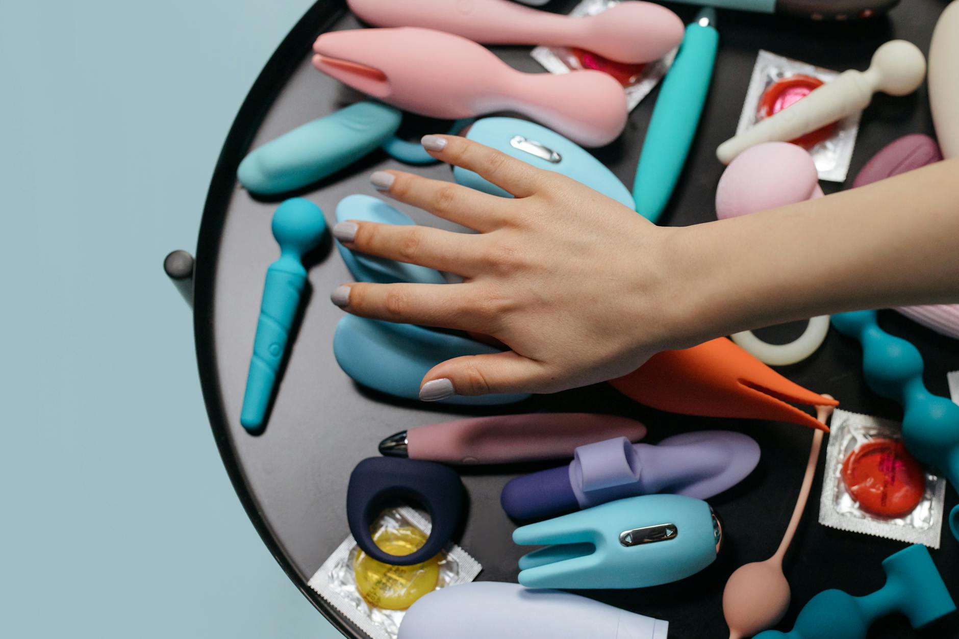 Due mani che tengono un vibratore blu luminoso su sfondo viola