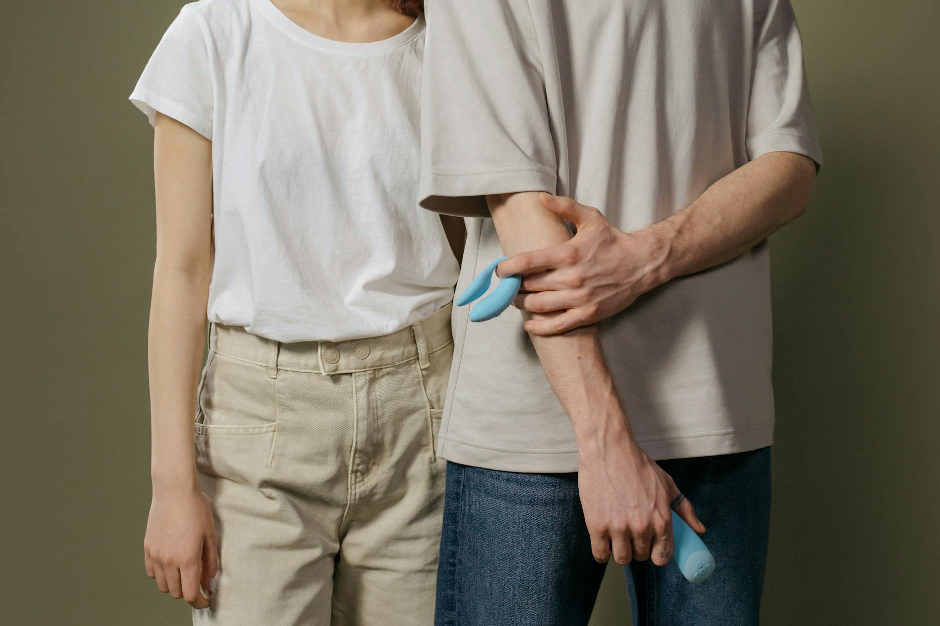 Una giovane coppia che si abbraccia tenendo in mano un vibratore blu, simbolo di intimità moderna e comunicazione di coppia.