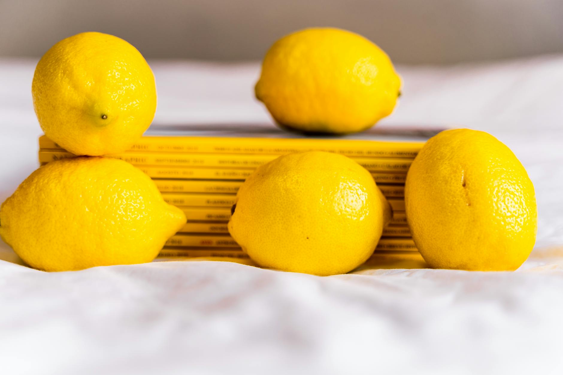 Mano che tiene un limone giallo fresco su sfondo rosa delicato